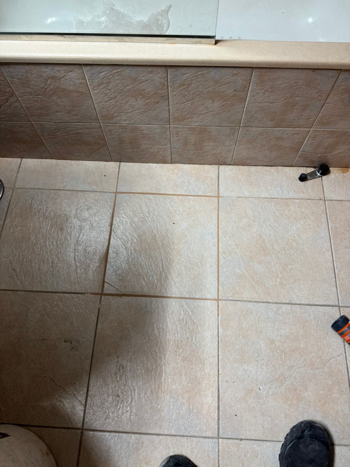 Suelo del baño con los azulejos reinstalados junto a la bañera, sin rastro de la reparación